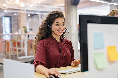 客戶支持電話運營商在計算機上工作。Happy Call Center Agent在辦公室工作的支持熱線工作。在與耳機上與客戶交談時，微笑著呼叫中心代理。